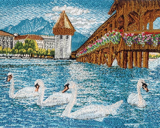 Detailed embroidery depicting swans swimming in a blue river alongside a wooden bridge with flowers and distant mountains.