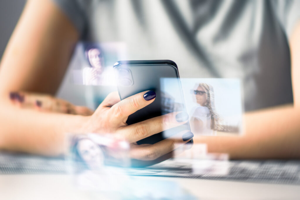 Person holding a smartphone utilizing photo vectorization and image processing software with floating preview tiles.